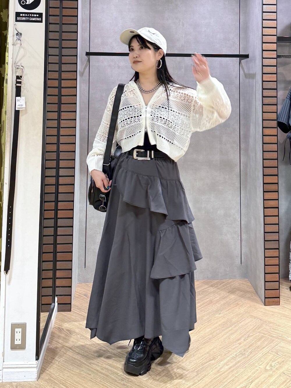 グレー系のスカート、ブラック系のスニーカー、ホワイト系のパーカーを着用したレディースの夏コーディネートの7枚目の写真