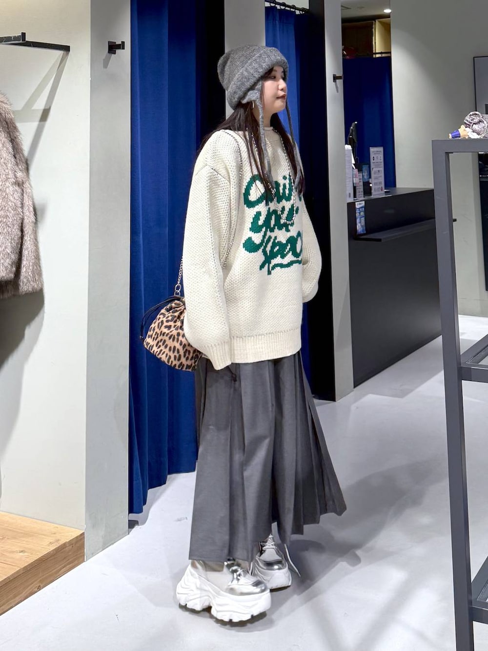 ホワイト系のブーツ、ホワイト系のニット/セーター、グレー系のスカートを着用したレディースの冬コーディネートの3枚目の写真