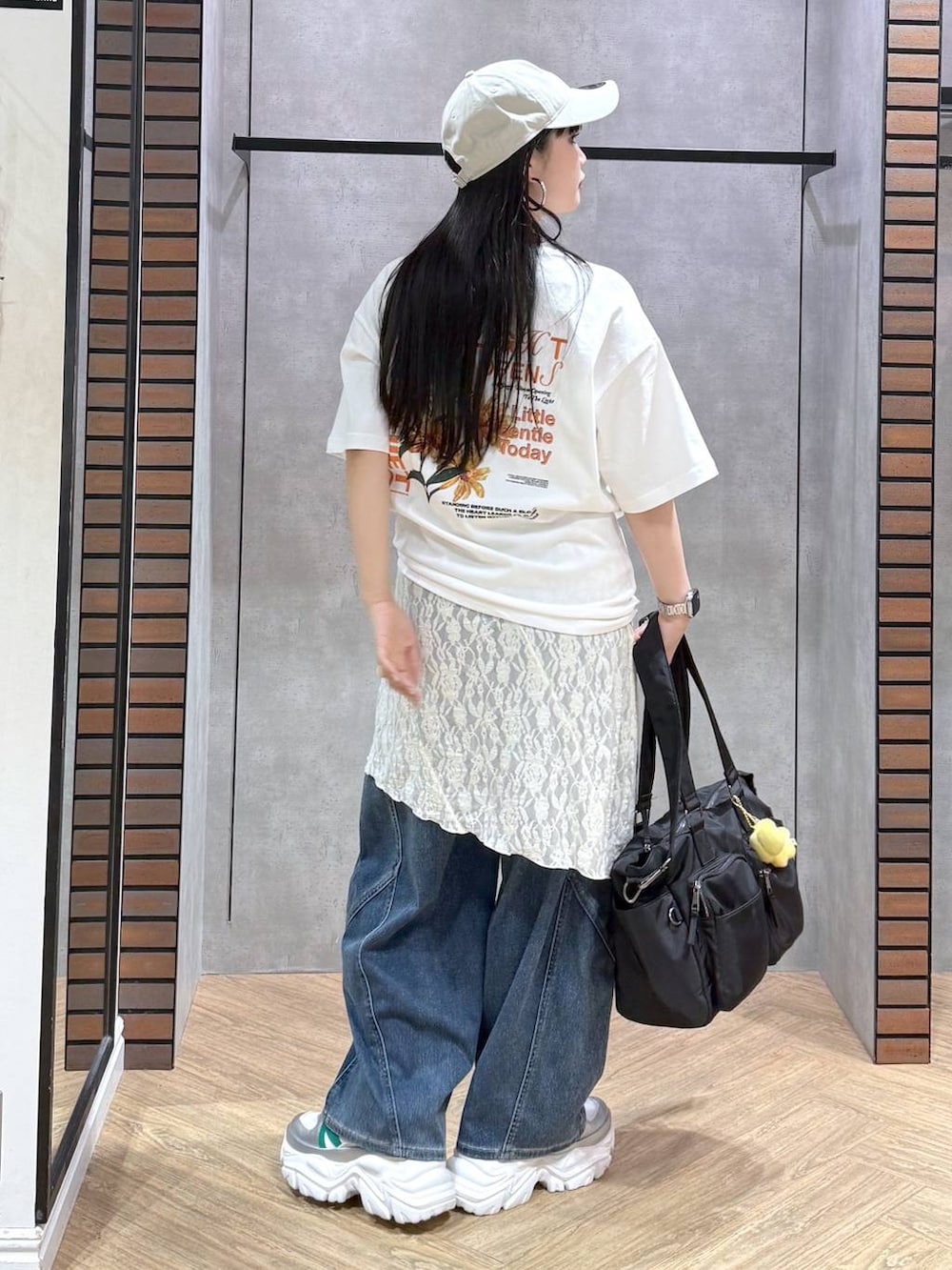 ホワイト系のスニーカー、ブラック系のボストンバッグ、ブルー系のデニムパンツを着用したレディースの春コーディネートの3枚目の写真