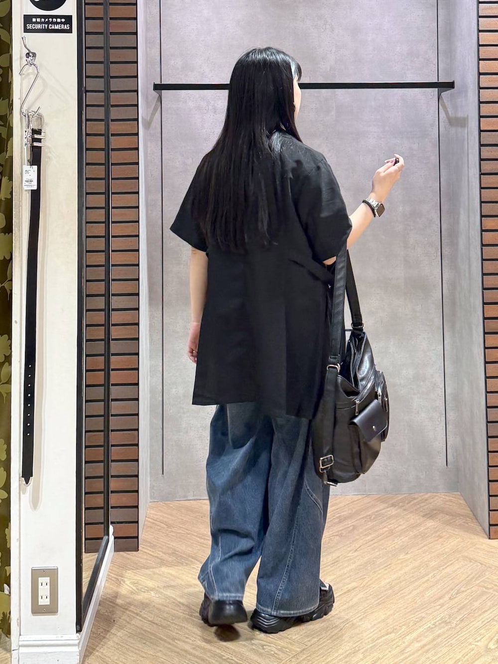 ブラック系のショルダーバッグ、ブルー系のデニムパンツ、ブラック系のサンダルを着用したレディースの春コーディネートの6枚目の写真