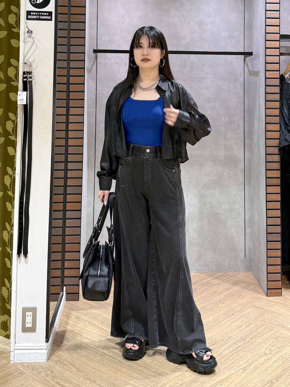 ブラック系のデニムパンツ、ブルー系のタンクトップ、ブラック系のサンダルを着用したレディースの夏コーディネートの2枚目の写真