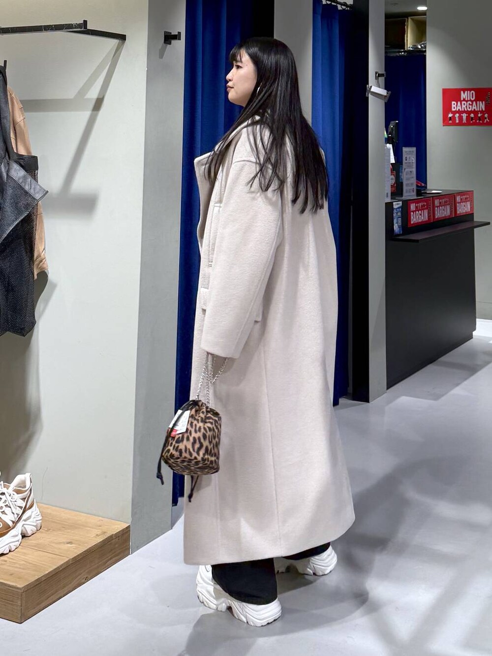 ホワイト系のスニーカー、ベージュ系のチェスターコート、ブラウン系のニット/セーターを着用したレディースの冬コーディネートの4枚目の写真