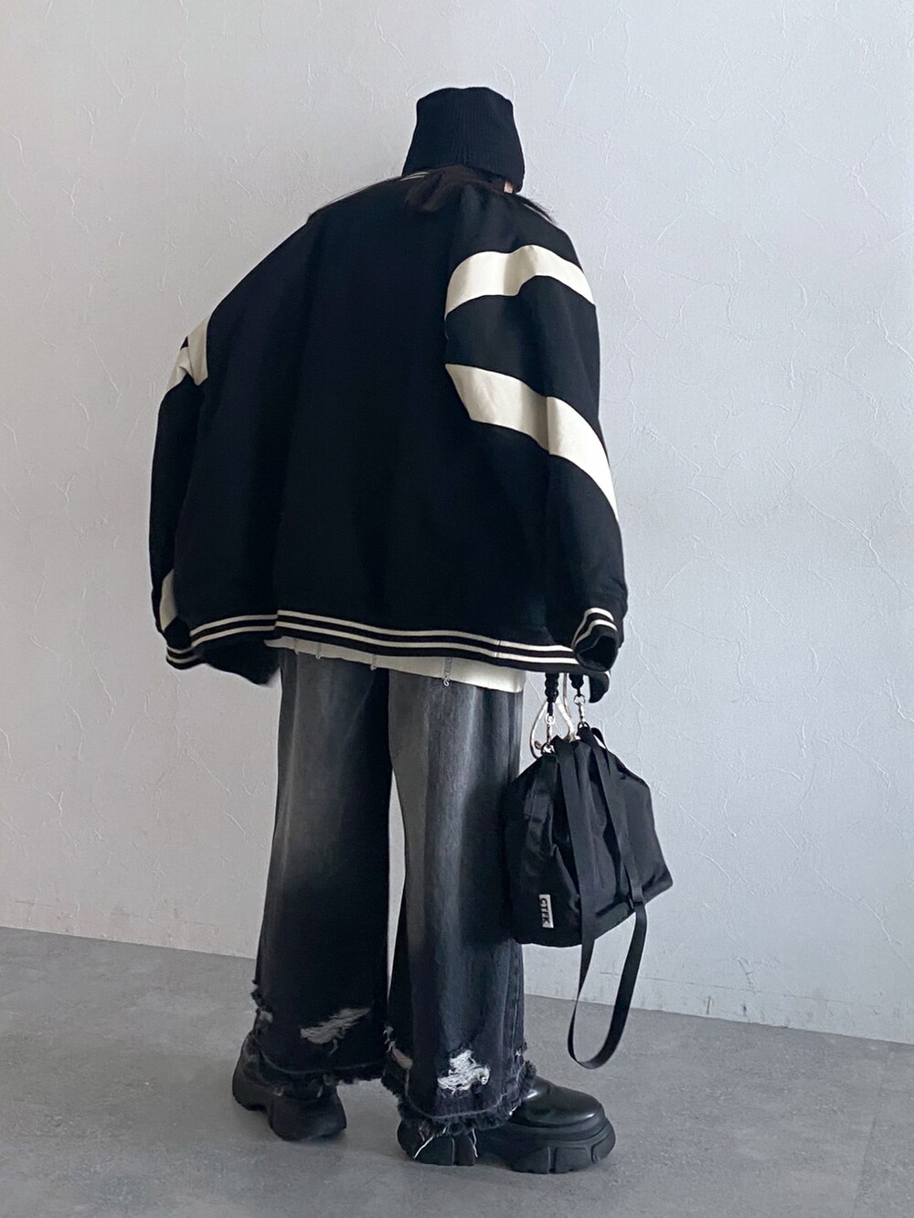 ブラック系のデニムパンツ、ブラック系のスタジャン、ホワイト系のニット/セーターを着用したレディースの秋コーディネートの4枚目の写真