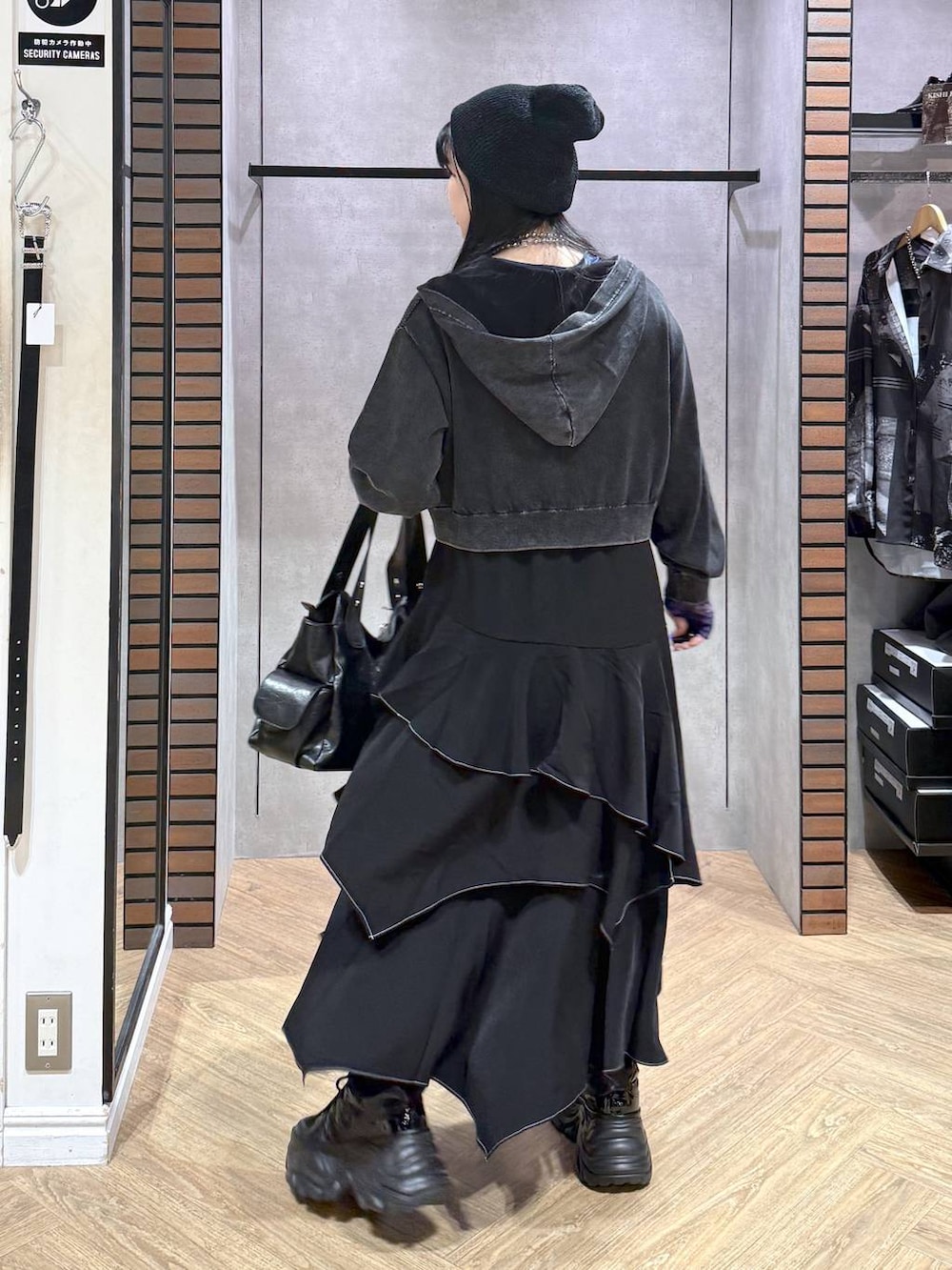 グレー系のパーカー、ブラック系のスカート、ブラック系のスニーカーを着用したレディースの秋コーディネートの5枚目の写真