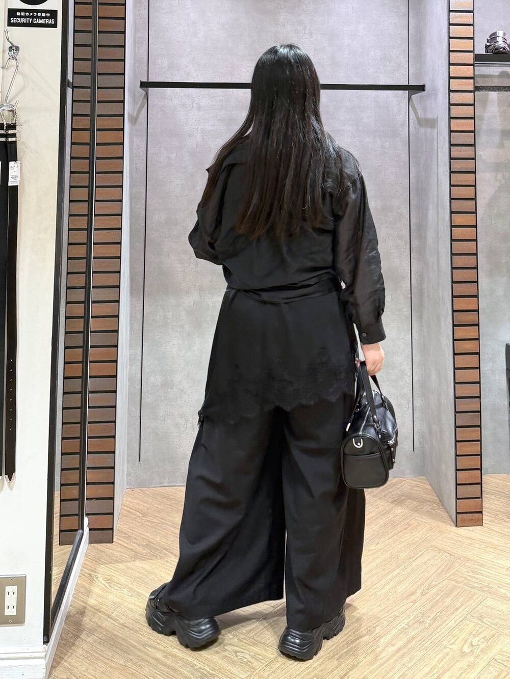 ブラック系のショルダーバッグ、ブラック系のチュニック、ブラック系のスラックスを着用したレディースの夏コーディネートの3枚目の写真