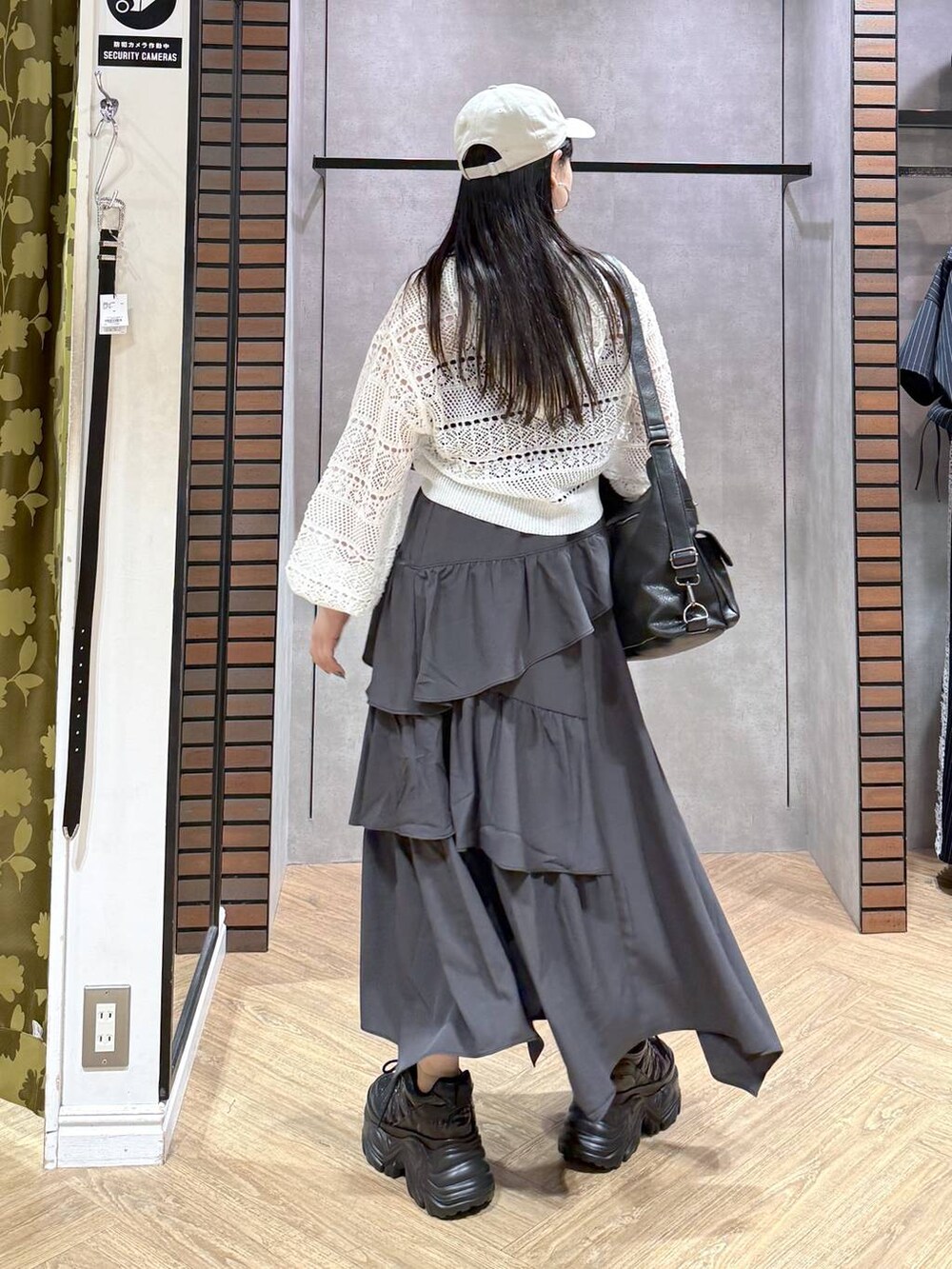 グレー系のスカート、ブラック系のスニーカー、ホワイト系のパーカーを着用したレディースの夏コーディネートの8枚目の写真