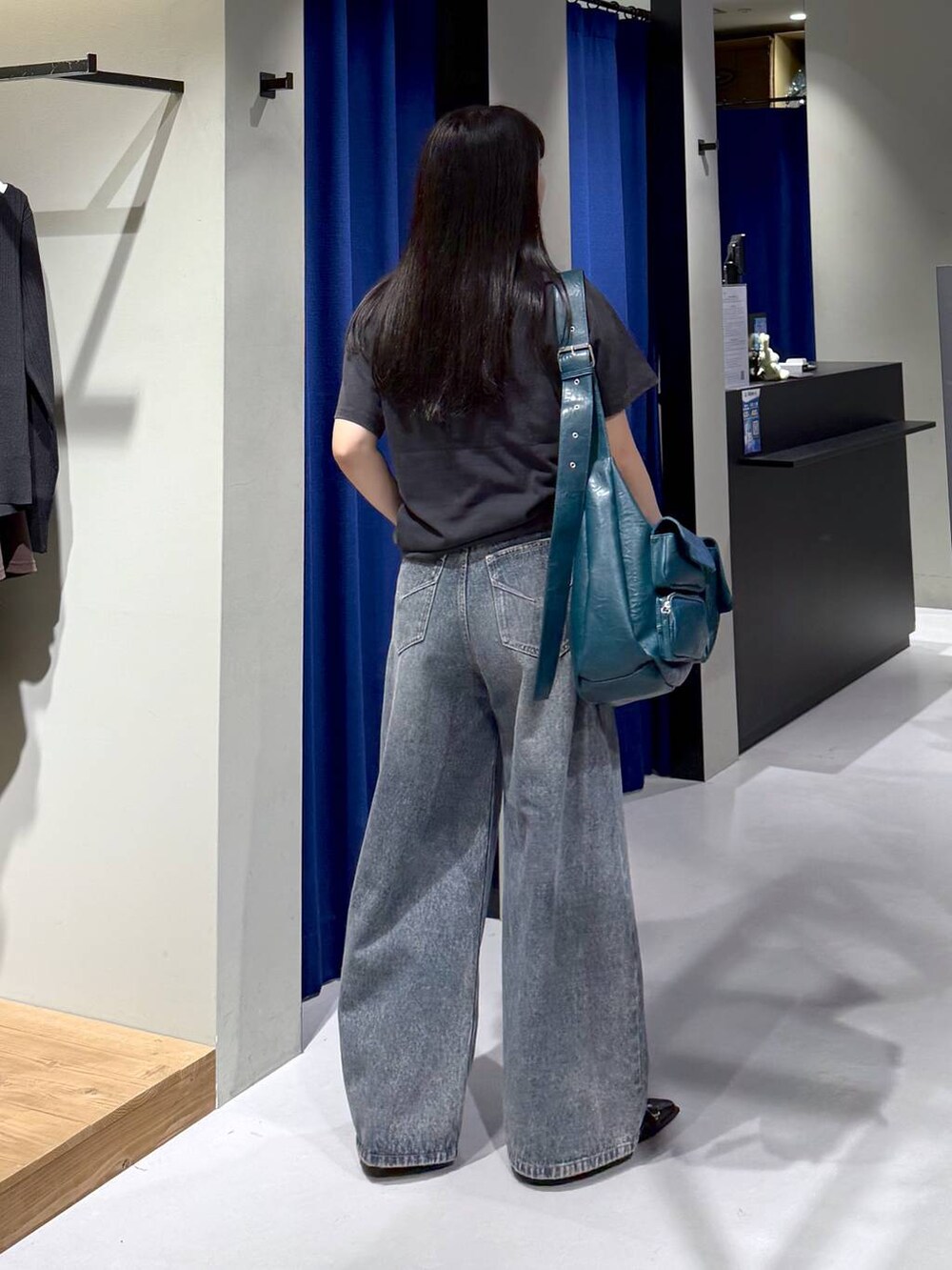 ブルー系のデニムパンツ、グリーン系のショルダーバッグ、ブラック系のパンプスを着用したレディースの秋コーディネートの3枚目の写真