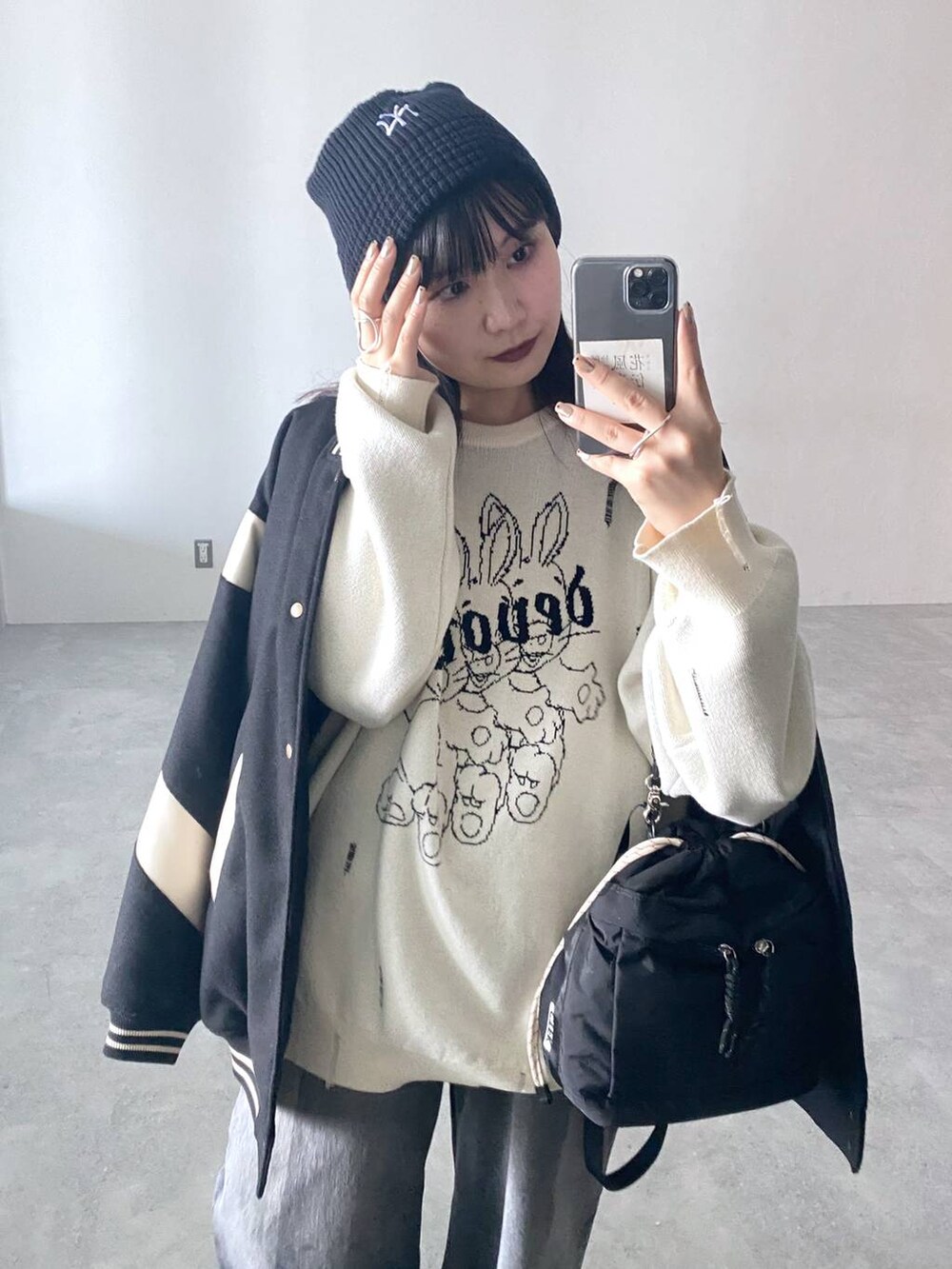 ブラック系のデニムパンツ、ブラック系のスタジャン、ブラック系のショルダーバッグを着用したレディースの秋コーディネートの2枚目の写真