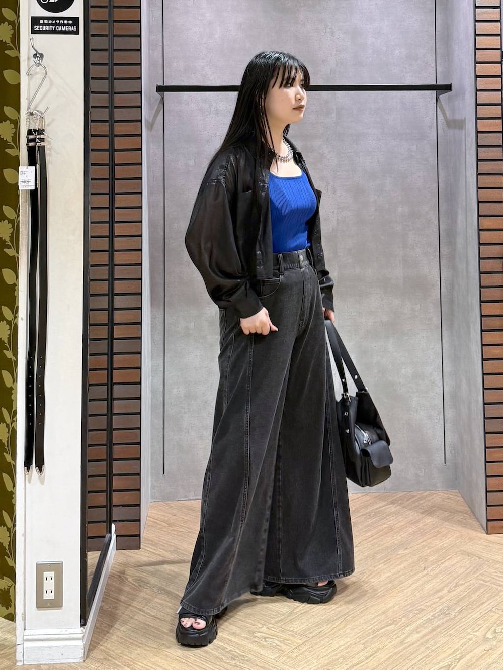 ブラック系のデニムパンツ、ブルー系のタンクトップ、ブラック系のサンダルを着用したレディースの夏コーディネートの4枚目の写真