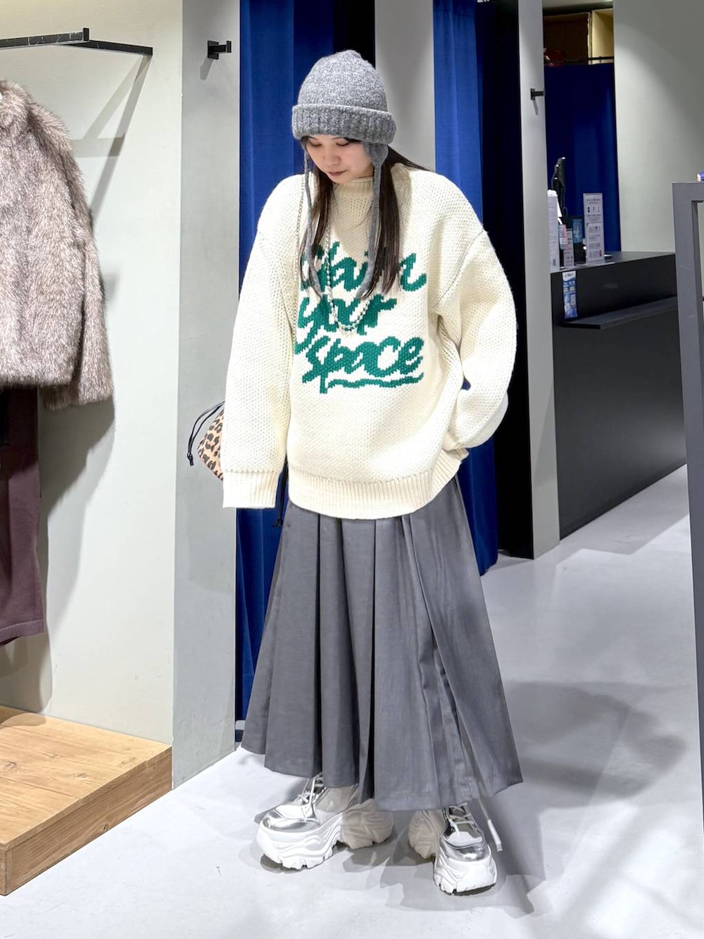 ホワイト系のブーツ、ホワイト系のニット/セーター、グレー系のスカートを着用したレディースの冬コーディネートの4枚目の写真