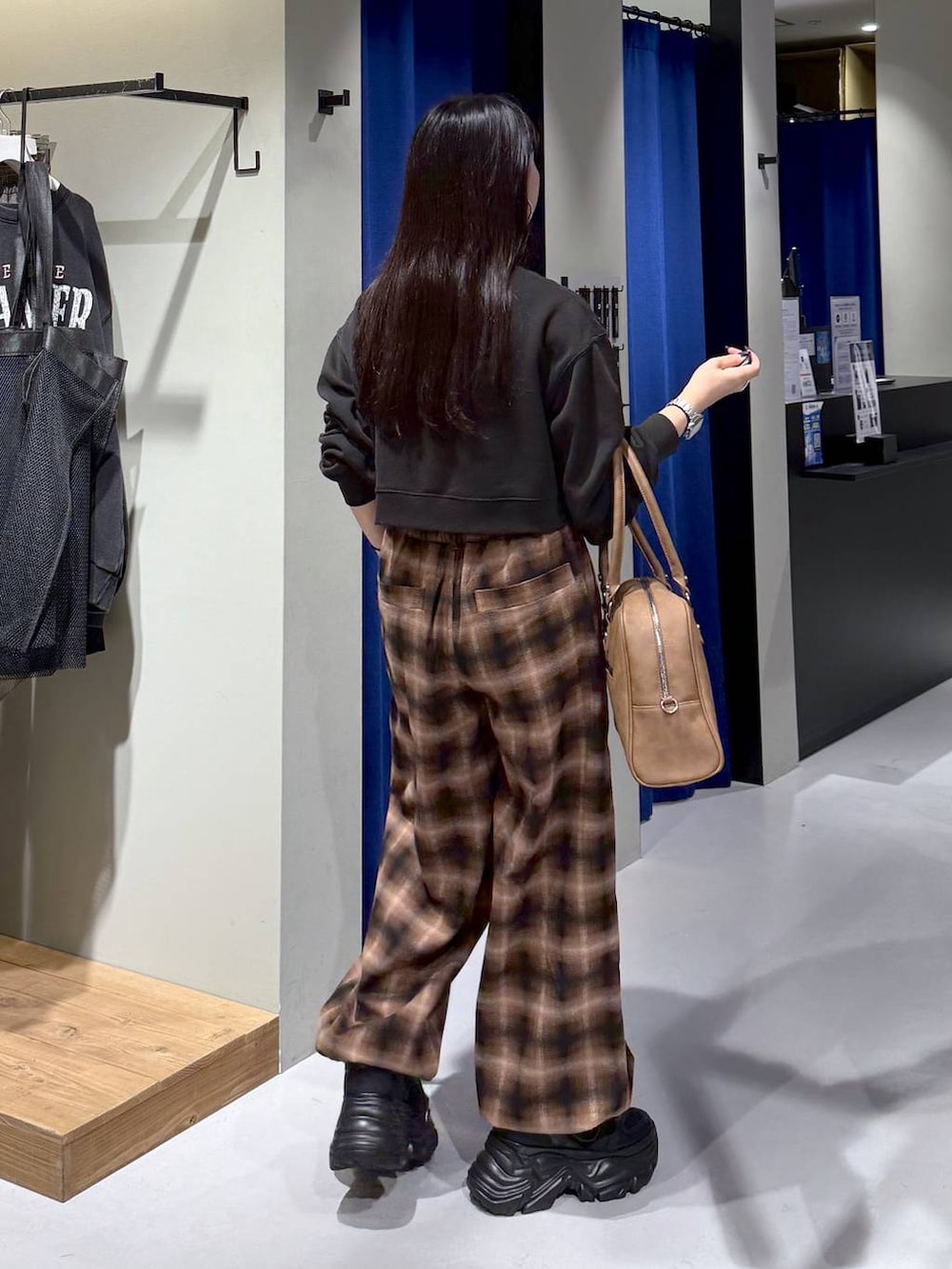 ブラック系のスニーカー、イエロー系のボストンバッグ、ブラウン系のスラックスを着用したレディースの秋コーディネートの3枚目の写真