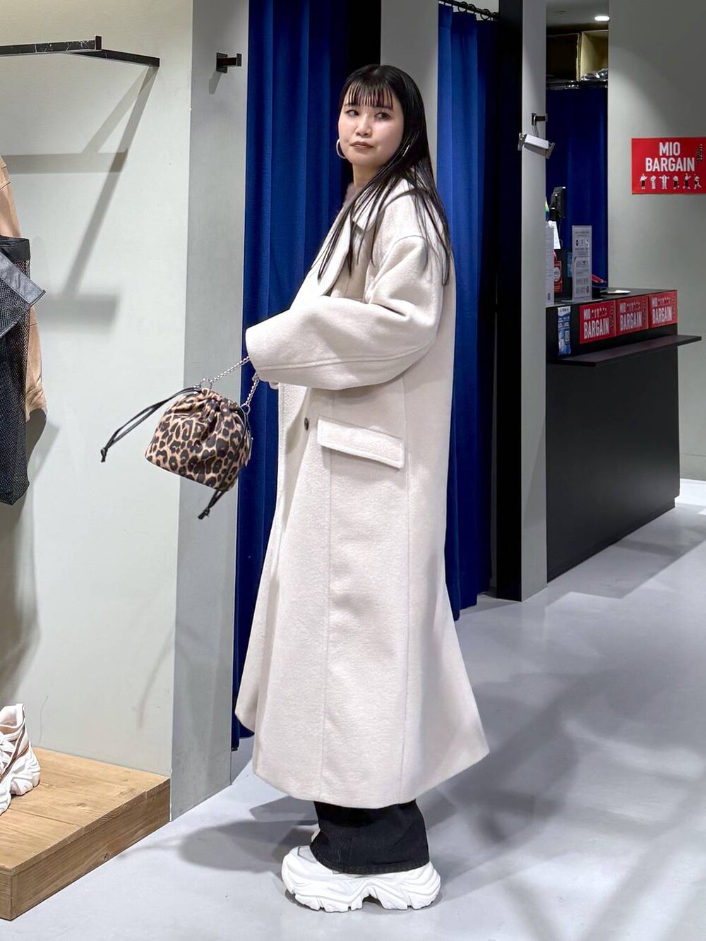 ホワイト系のスニーカー、ベージュ系のチェスターコート、ブラウン系のニット/セーターを着用したレディースの冬コーディネートの6枚目の写真