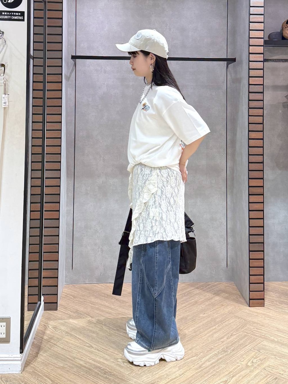 ホワイト系のスニーカー、ブラック系のボストンバッグ、ブルー系のデニムパンツを着用したレディースの春コーディネートの4枚目の写真