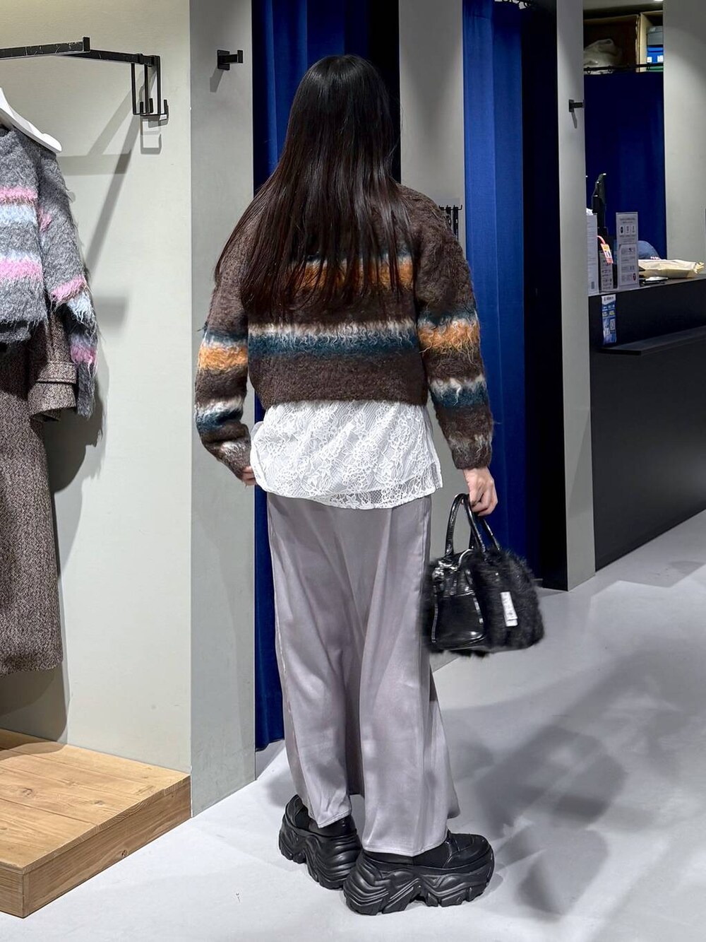 ブラック系のブーツ、ブラウン系のボストンバッグ、ホワイト系のシャツ/ブラウスを着用したレディースの冬コーディネートの4枚目の写真