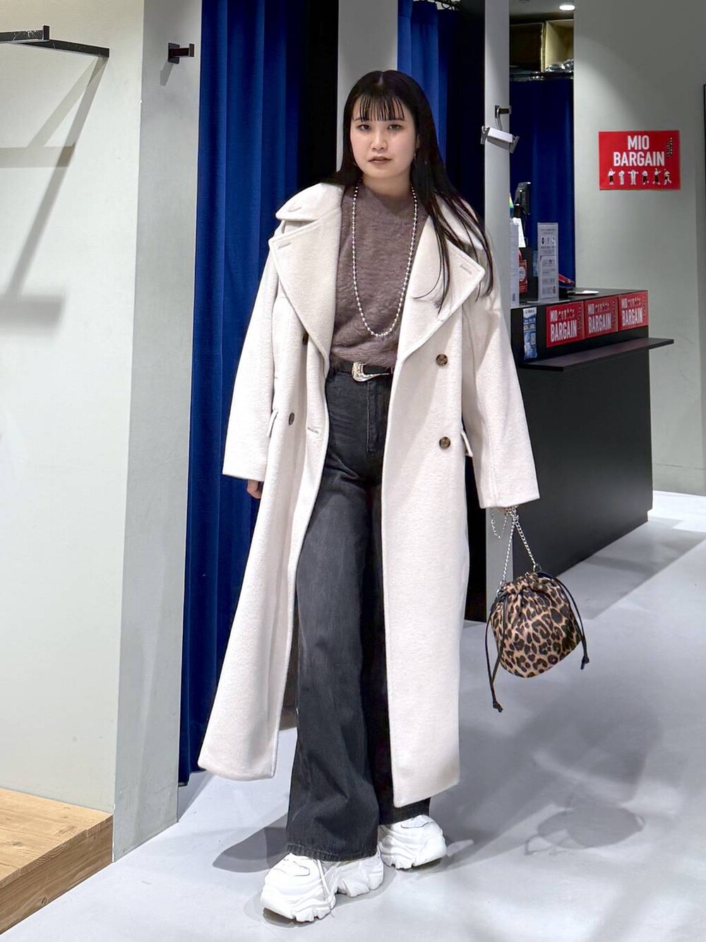 ホワイト系のスニーカー、ベージュ系のチェスターコート、ブラウン系のニット/セーターを着用したレディースの冬コーディネートの5枚目の写真