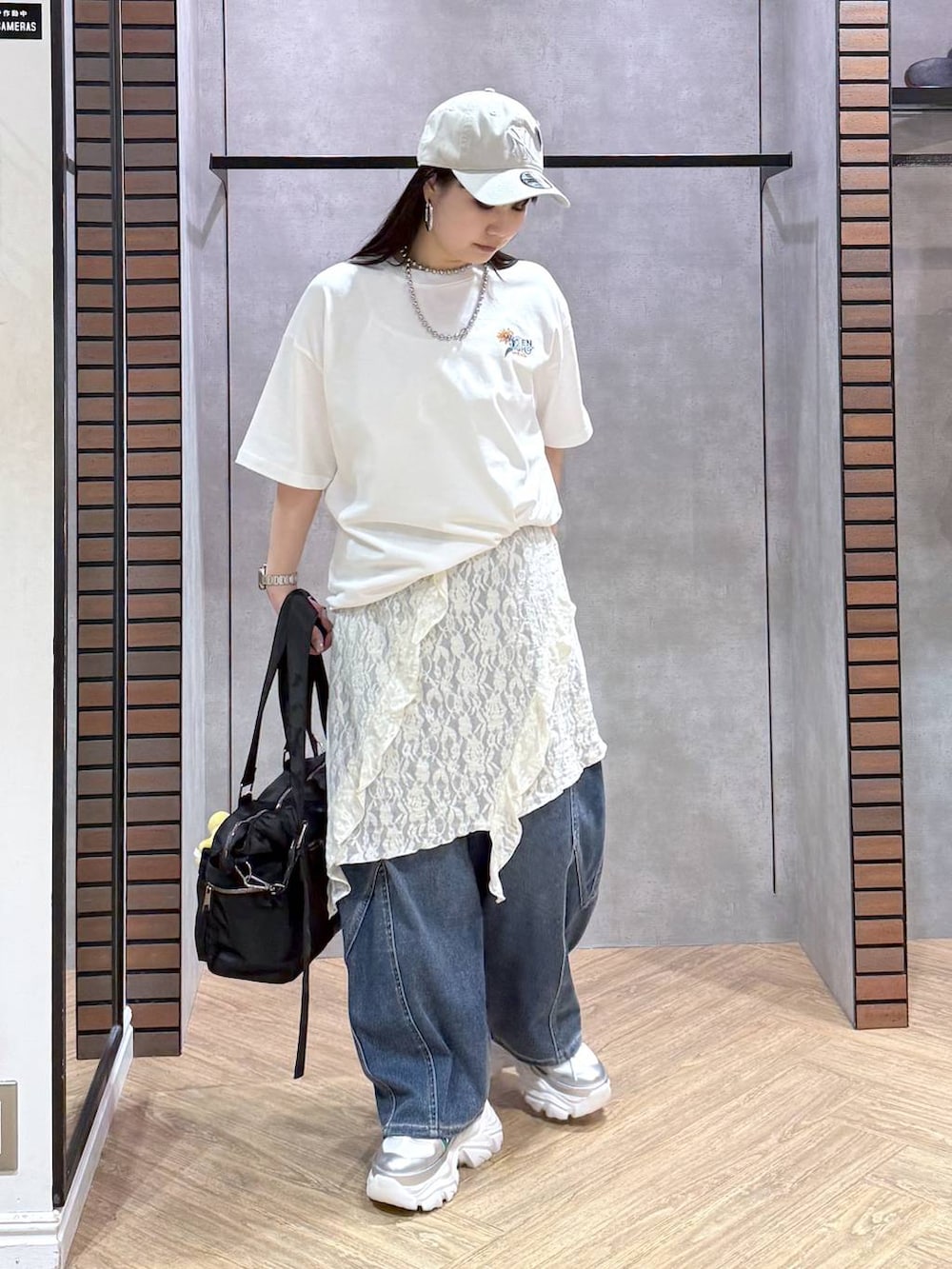 ホワイト系のスニーカー、ブラック系のボストンバッグ、ブルー系のデニムパンツを着用したレディースの春コーディネートの5枚目の写真