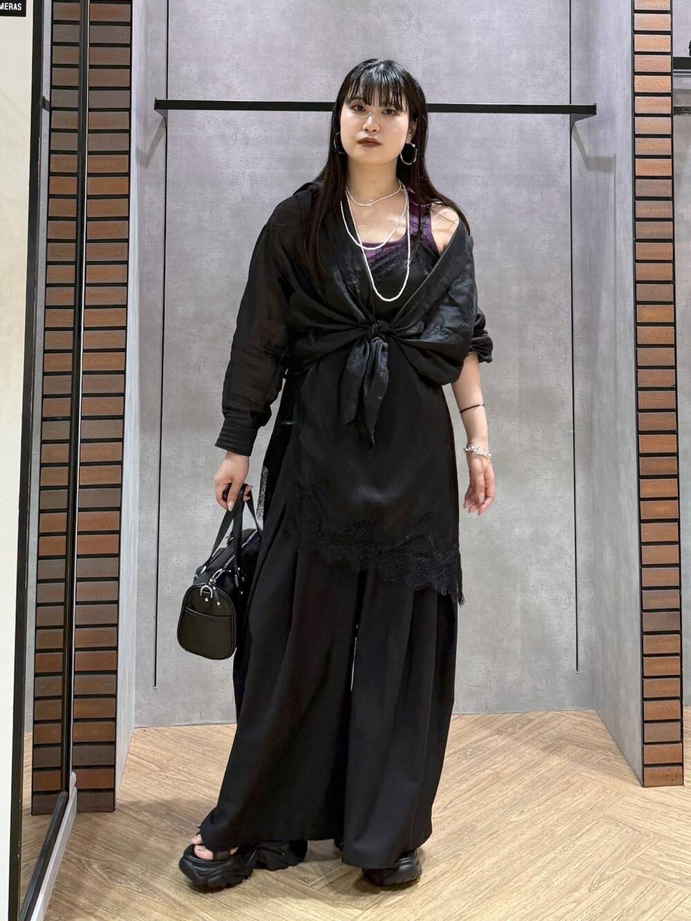 ブラック系のショルダーバッグ、ブラック系のチュニック、ブラック系のスラックスを着用したレディースの夏コーディネートの4枚目の写真