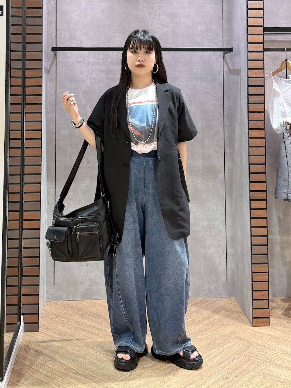 ブラック系のショルダーバッグ、ブルー系のデニムパンツ、ブラック系のサンダルを着用したレディースの春コーディネートの5枚目の写真