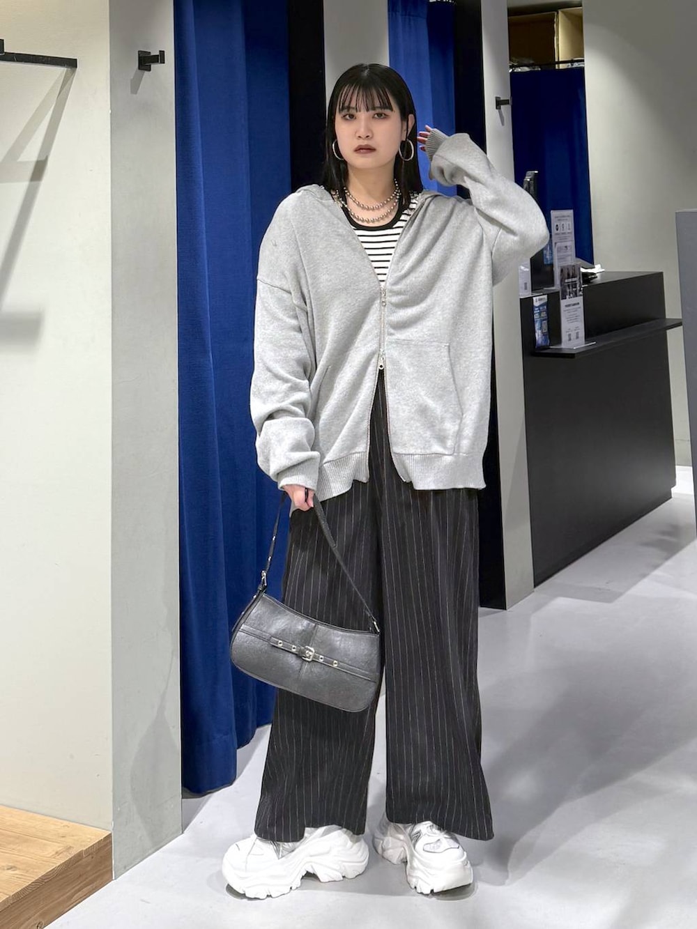 ホワイト系のスニーカー、ブラック系のハンドバッグ、ホワイト系のニット/セーターを着用したレディースの冬コーディネートの4枚目の写真