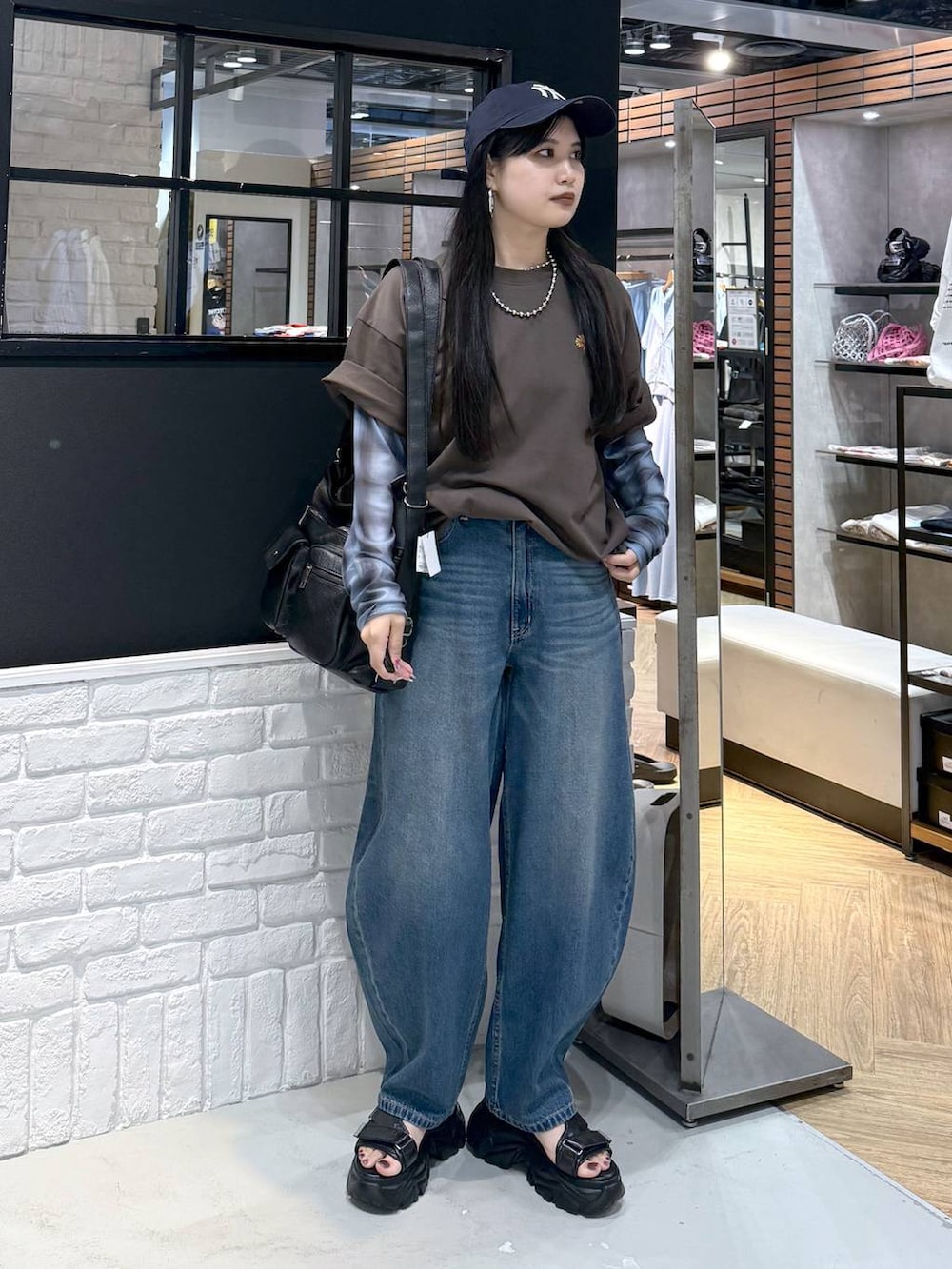 ブラウン系のショルダーバッグ、ブラック系のサンダル、ブラウン系のTシャツ/カットソーを着用したレディースの夏コーディネートの6枚目の写真
