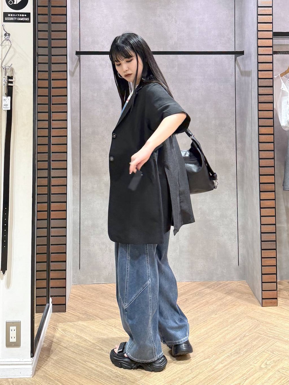 ブラック系のショルダーバッグ、ブルー系のデニムパンツ、ブラック系のサンダルを着用したレディースの春コーディネートの4枚目の写真
