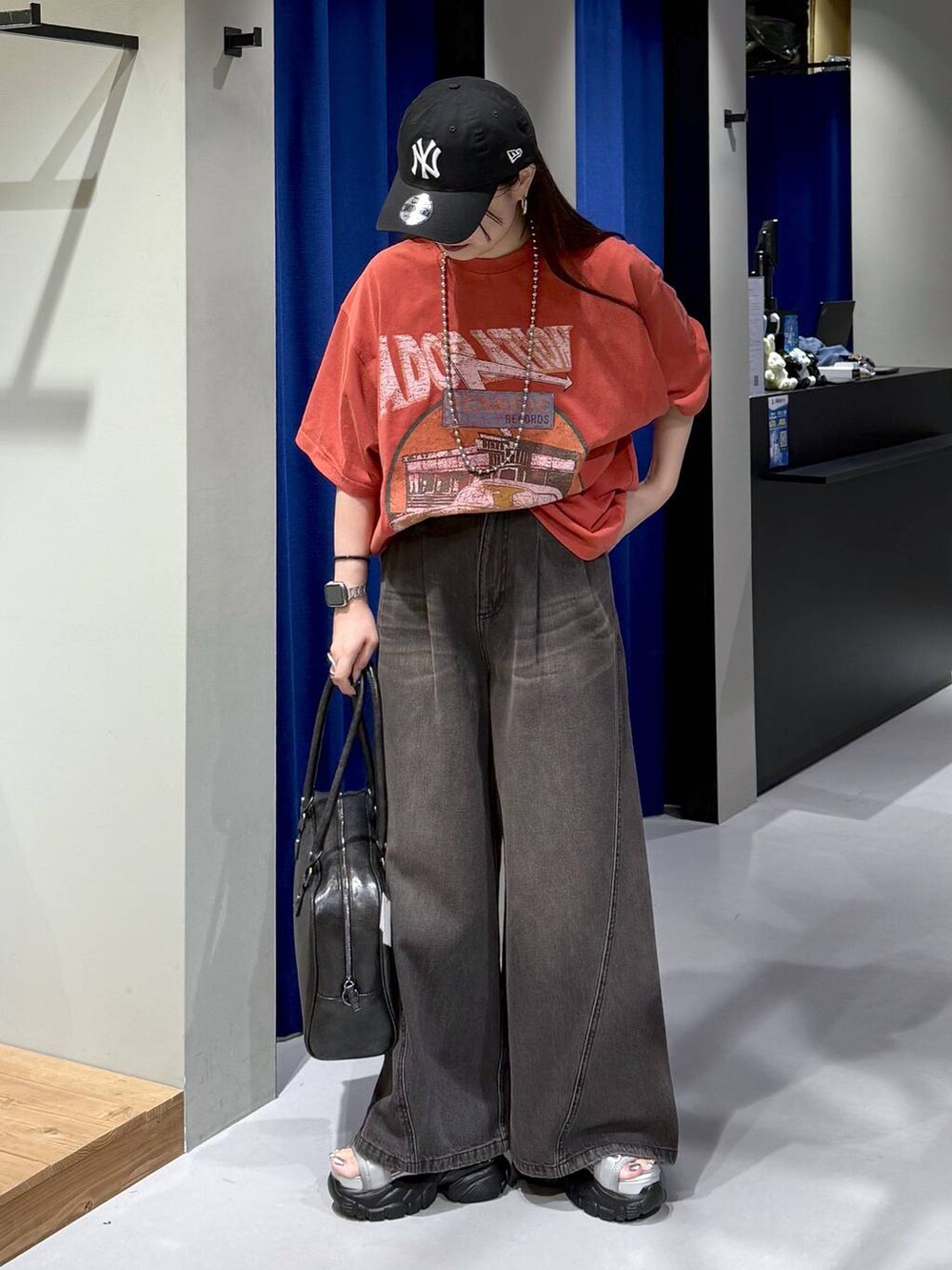 ブラック系のデニムパンツ、ブラック系のボストンバッグ、グレー系のサンダルを着用したレディースの夏コーディネートの4枚目の写真
