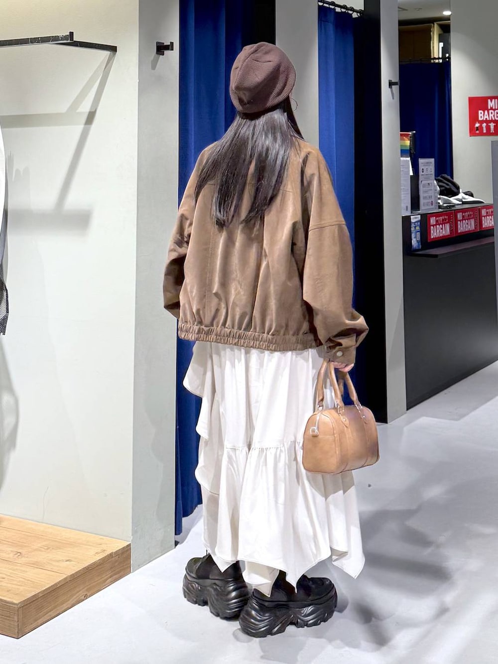 ブラック系のブーツ、ベージュ系のスカート、ブラウン系のボストンバッグを着用したレディースの春コーディネートの5枚目の写真