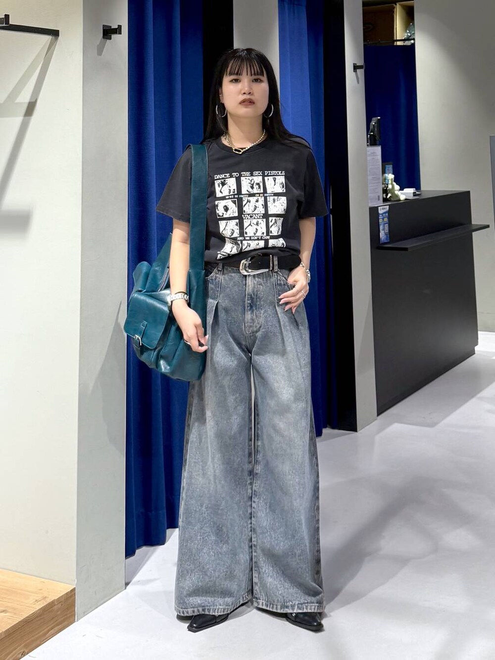 ブルー系のデニムパンツ、グリーン系のショルダーバッグ、ブラック系のパンプスを着用したレディースの秋コーディネートの4枚目の写真