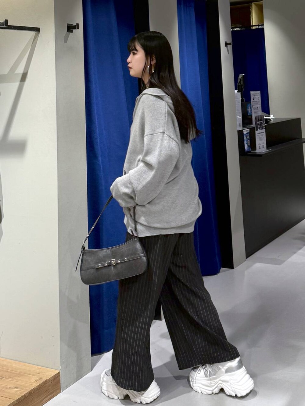 ホワイト系のスニーカー、ブラック系のハンドバッグ、ホワイト系のニット/セーターを着用したレディースの冬コーディネートの3枚目の写真