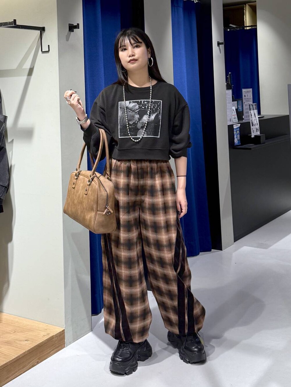 ブラック系のスニーカー、イエロー系のボストンバッグ、ブラウン系のスラックスを着用したレディースの秋コーディネートの2枚目の写真