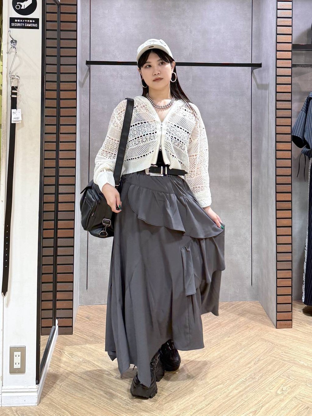 グレー系のスカート、ブラック系のスニーカー、ホワイト系のパーカーを着用したレディースの夏コーディネートの3枚目の写真