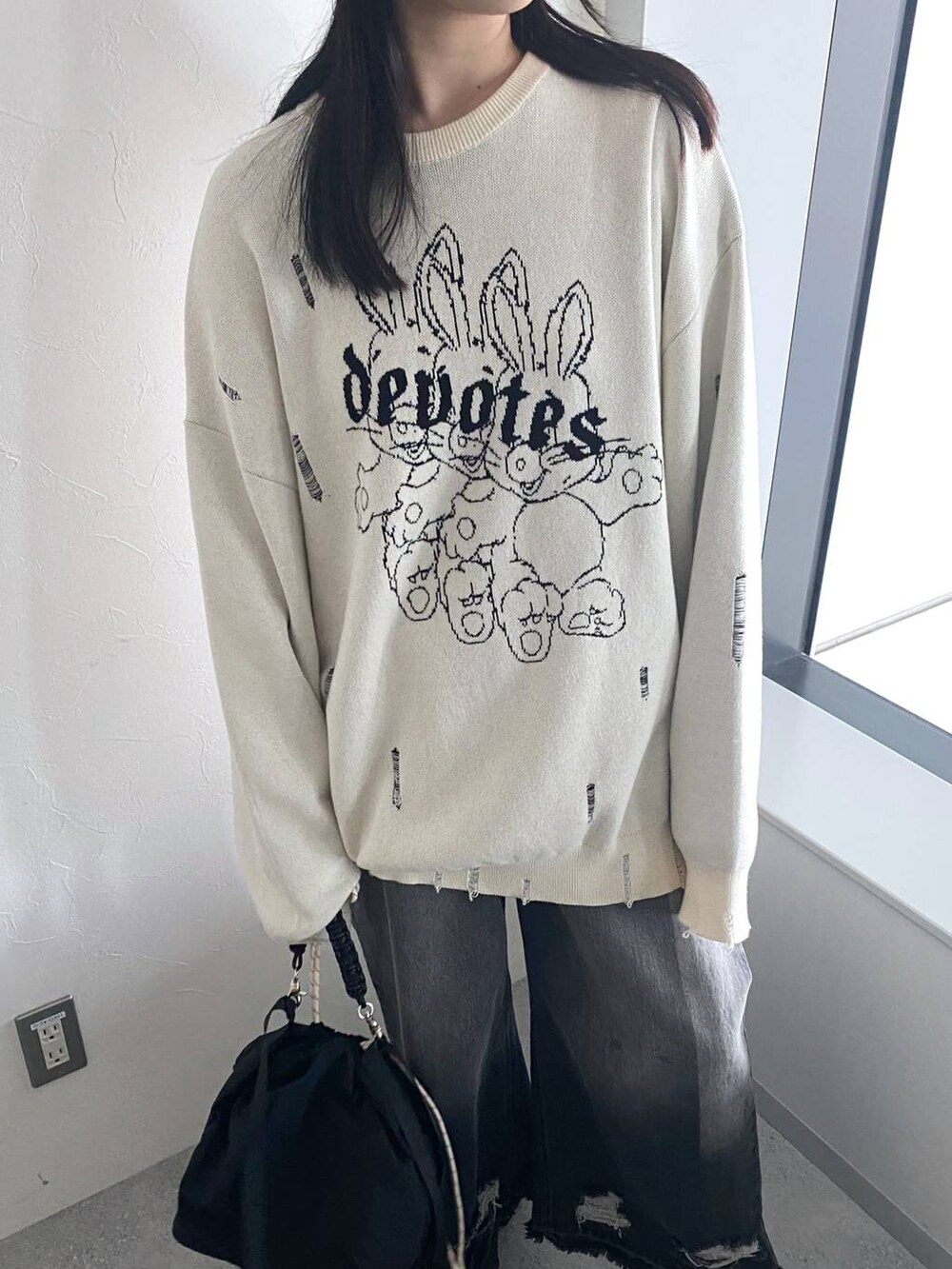 ブラック系のデニムパンツ、ブラック系のスタジャン、ブラック系のショルダーバッグを着用したレディースの秋コーディネートの3枚目の写真