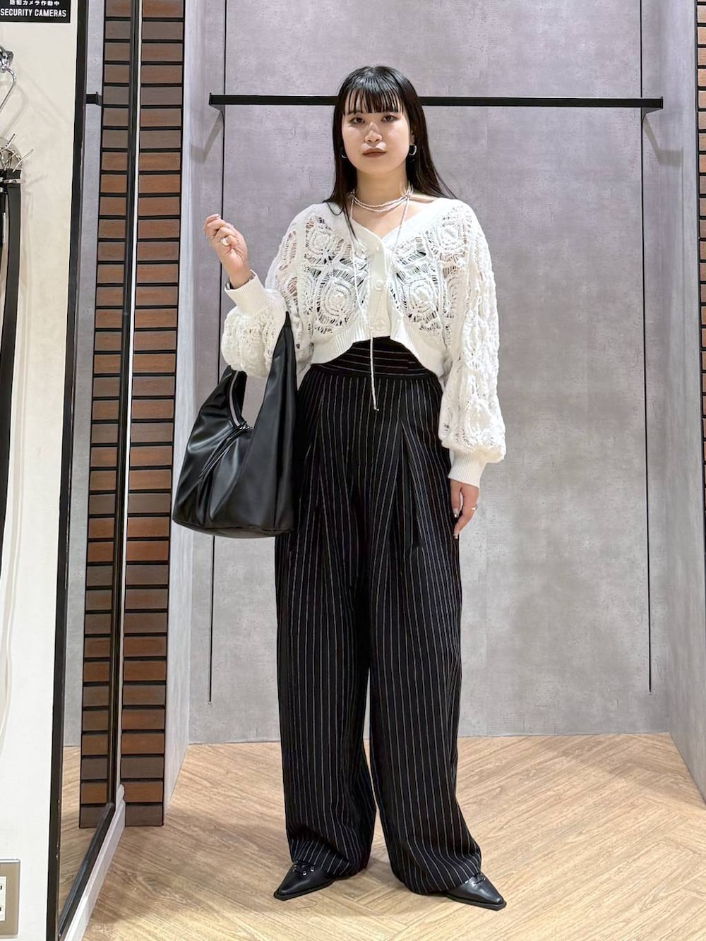 ブラック系のキャミソール、ホワイト系のカーディガン/ボレロ、ブラック系のトートバッグを着用したレディースの春コーディネートの4枚目の写真