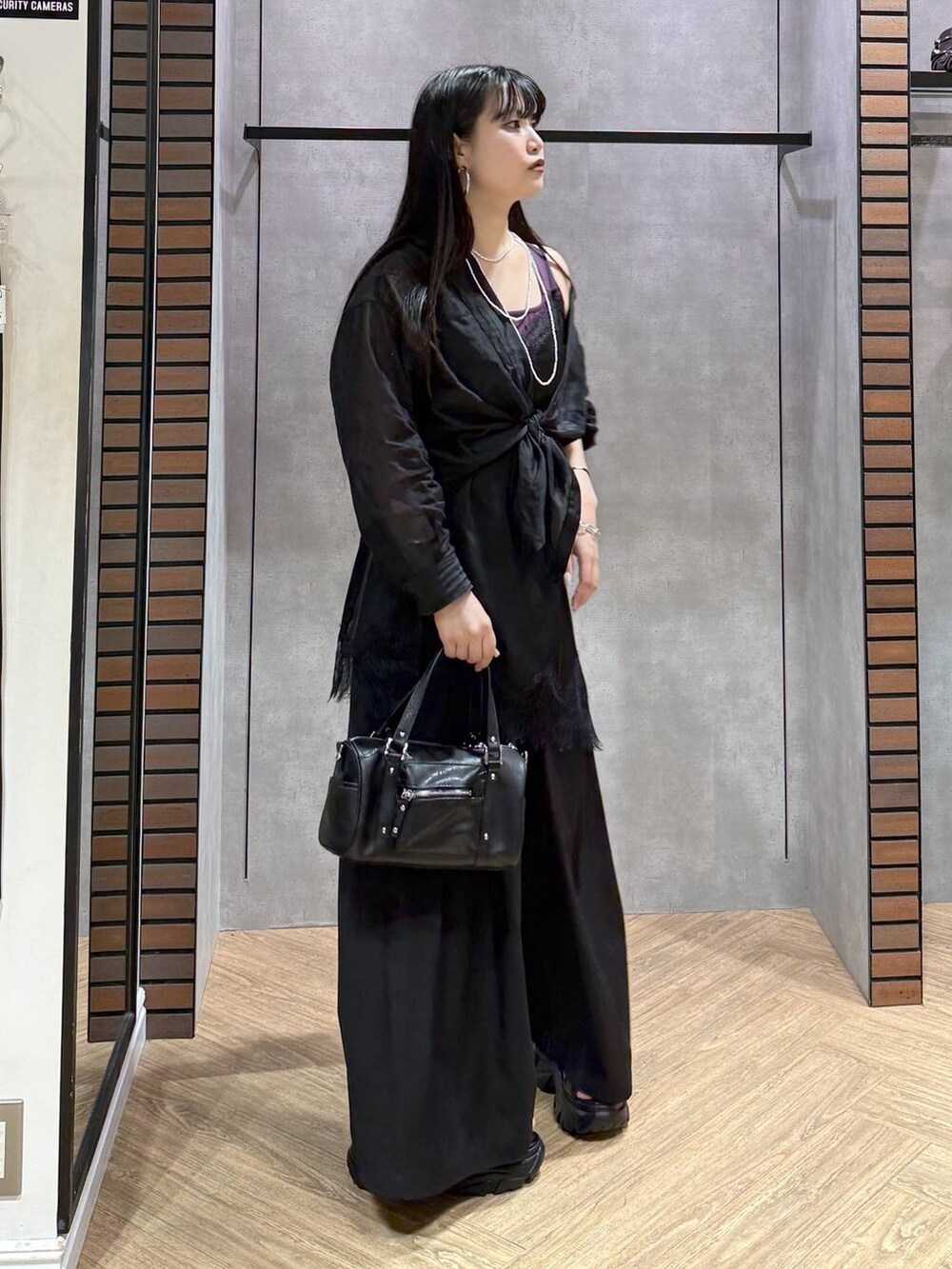 ブラック系のショルダーバッグ、ブラック系のチュニック、ブラック系のスラックスを着用したレディースの夏コーディネートの5枚目の写真