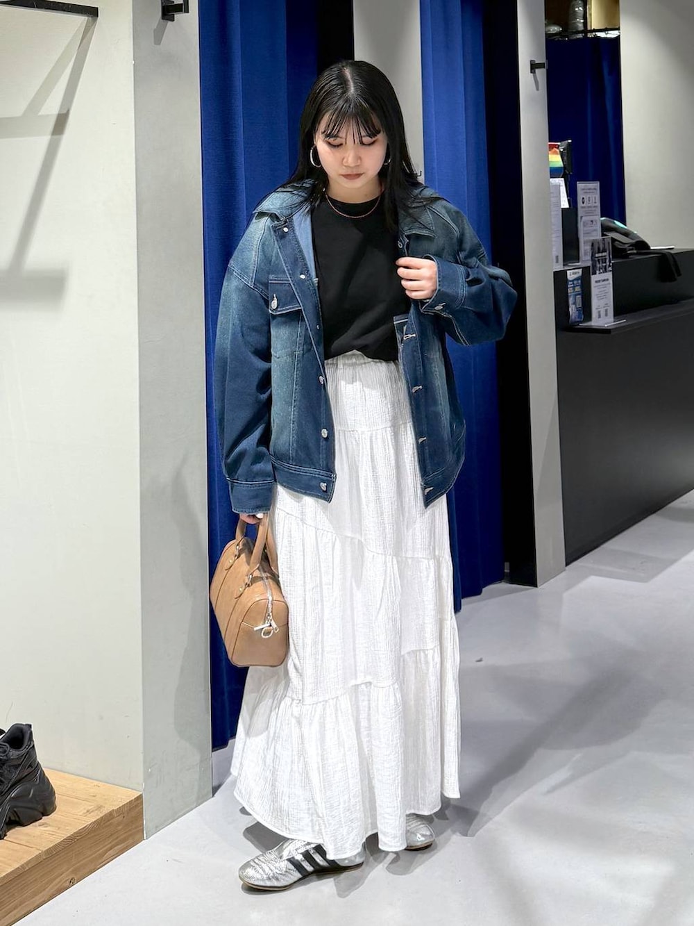 ブラック系のスウェット、ブラウン系のボストンバッグ、ブルー系のブルゾンを着用したレディースの春コーディネートの6枚目の写真