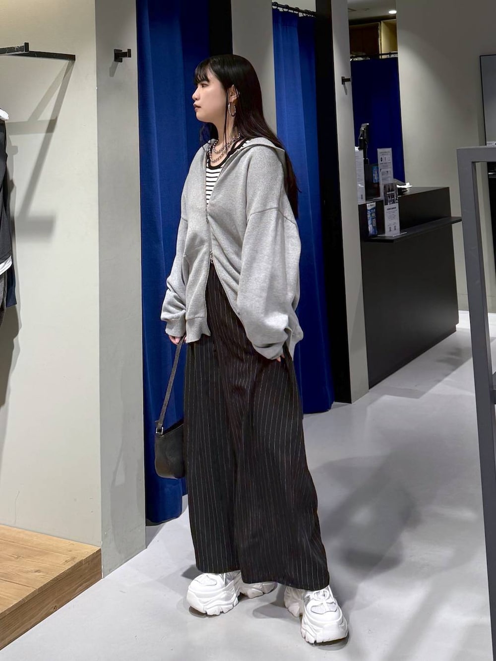 ホワイト系のスニーカー、ブラック系のハンドバッグ、ホワイト系のニット/セーターを着用したレディースの冬コーディネートの5枚目の写真