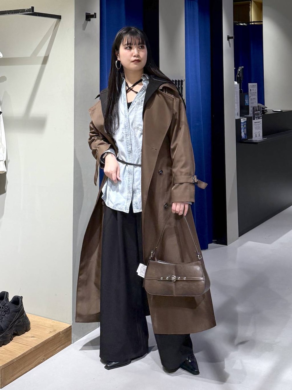 ブラック系のデニムパンツ、ブラウン系のトレンチコート、ブラウン系のハンドバッグを着用したレディースの冬コーディネートの2枚目の写真