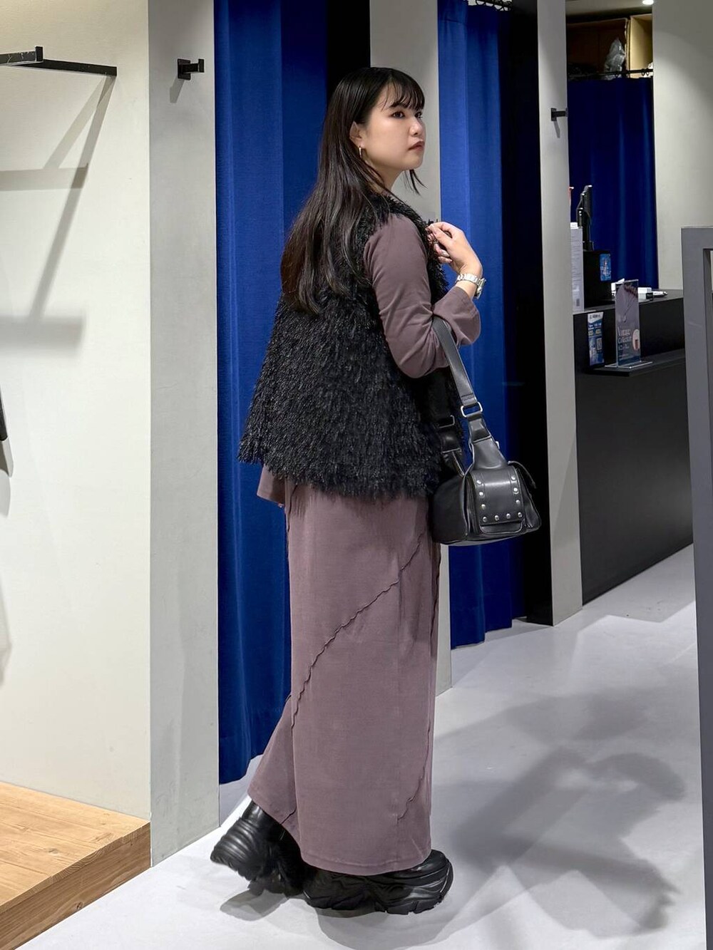 ブラック系のブーツ、ブラック系のショルダーバッグ、ブラック系のベストを着用したレディースの秋コーディネートの2枚目の写真