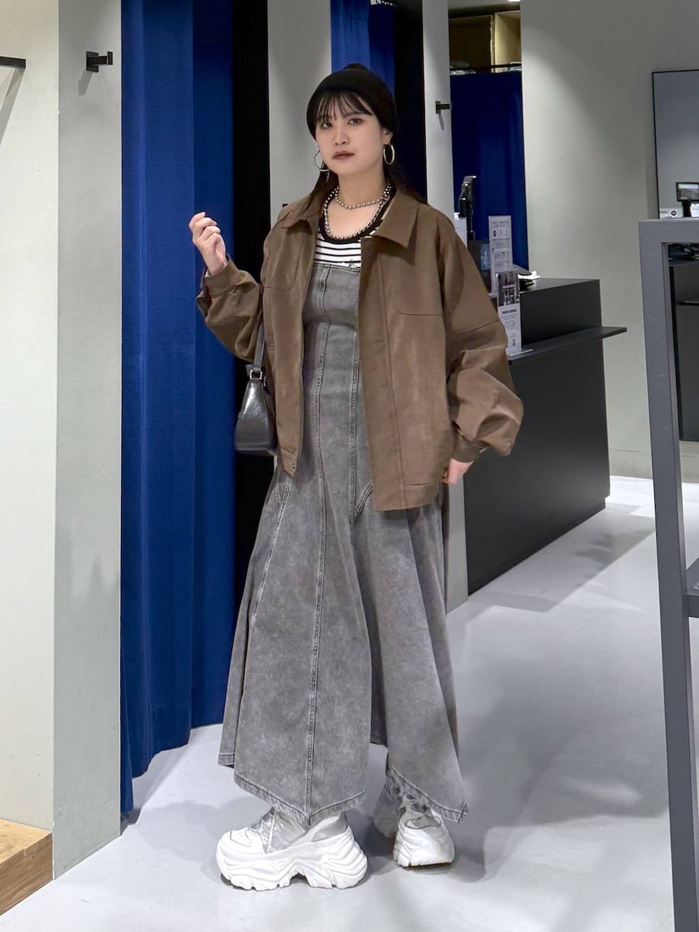 ホワイト系のスニーカー、ブラック系のハンドバッグ、ホワイト系のニット/セーターを着用したレディースの春コーディネートの2枚目の写真