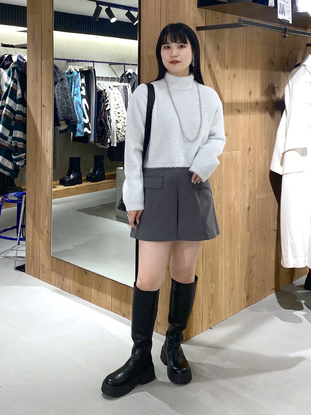 ブラック系のブーツ、ブラック系のショルダーバッグ、ホワイト系のニット/セーターを着用したレディースの冬コーディネートの3枚目の写真