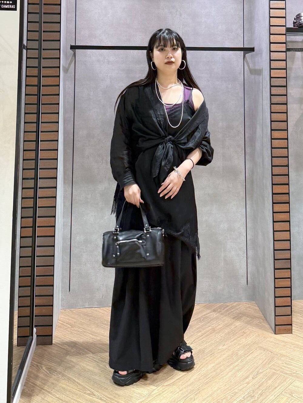 ブラック系のショルダーバッグ、ブラック系のチュニック、ブラック系のスラックスを着用したレディースの夏コーディネートの6枚目の写真