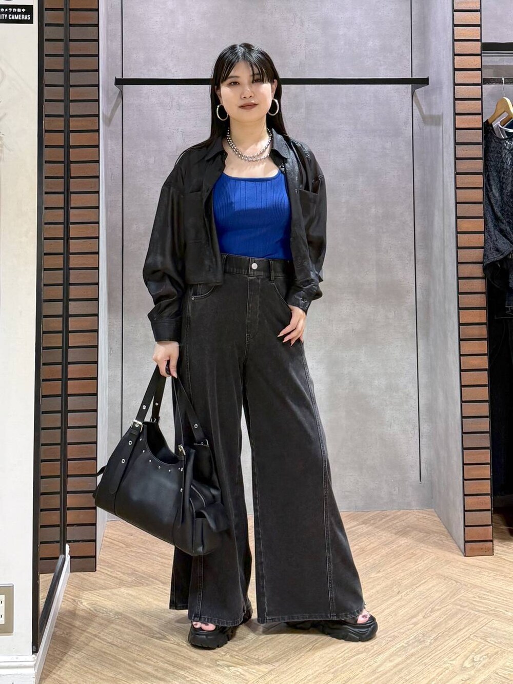 ブラック系のデニムパンツ、ブルー系のタンクトップ、ブラック系のサンダルを着用したレディースの夏コーディネートの7枚目の写真
