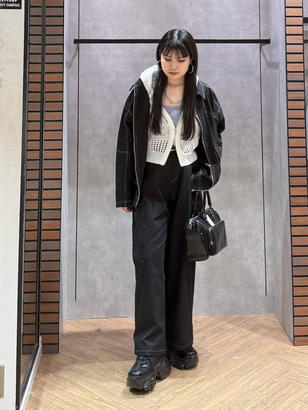 ブラック系のスニーカー、ブラック系のショルダーバッグ、ブルー系のタンクトップを着用したレディースの春コーディネートの4枚目の写真