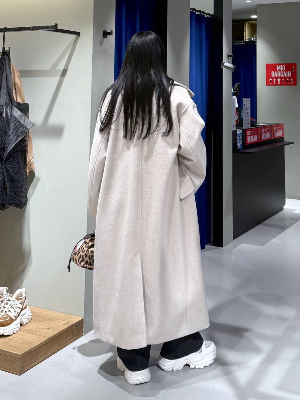 ホワイト系のスニーカー、ベージュ系のチェスターコート、ブラウン系のニット/セーターを着用したレディースの冬コーディネートの2枚目の写真