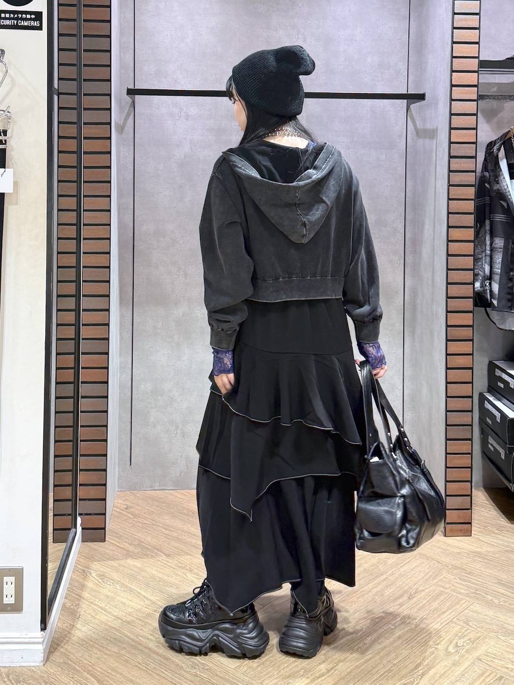 グレー系のパーカー、ブラック系のスカート、ブラック系のスニーカーを着用したレディースの秋コーディネートの4枚目の写真