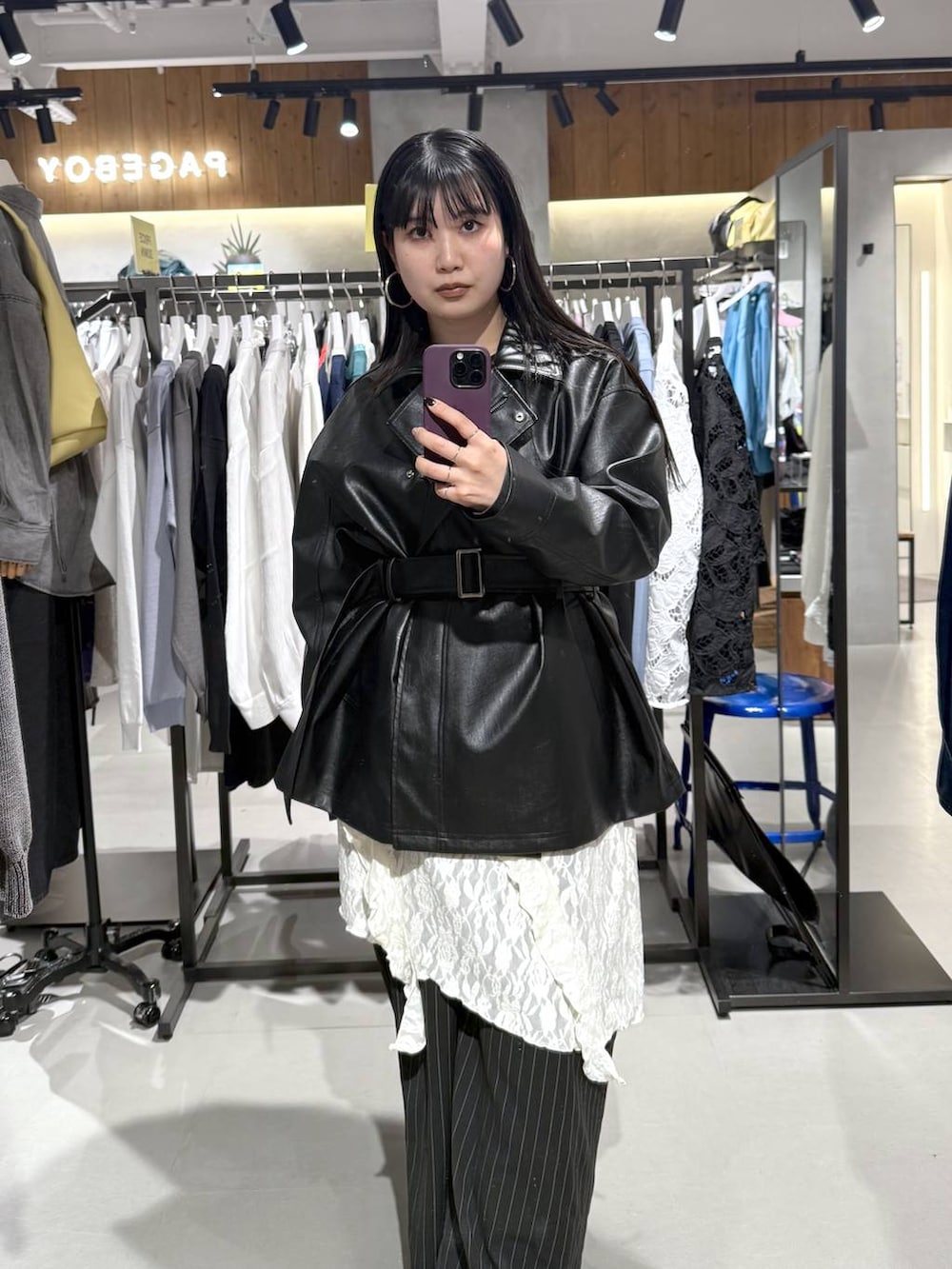 ホワイト系のチュニック、ブラック系のライダースジャケットを着用したレディースの春コーディネートの2枚目の写真