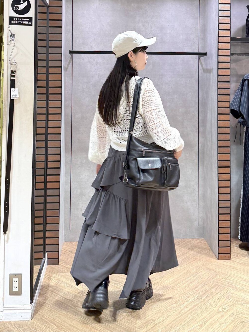 グレー系のスカート、ブラック系のスニーカー、ホワイト系のパーカーを着用したレディースの夏コーディネートの4枚目の写真