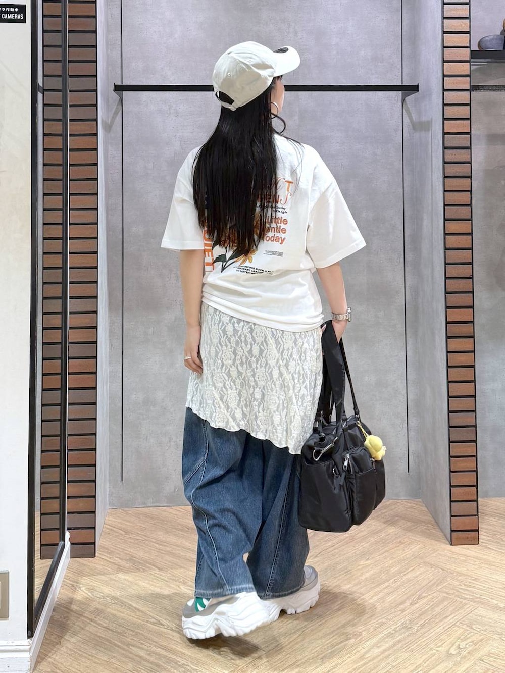 ホワイト系のスニーカー、ブラック系のボストンバッグ、ブルー系のデニムパンツを着用したレディースの春コーディネートの6枚目の写真