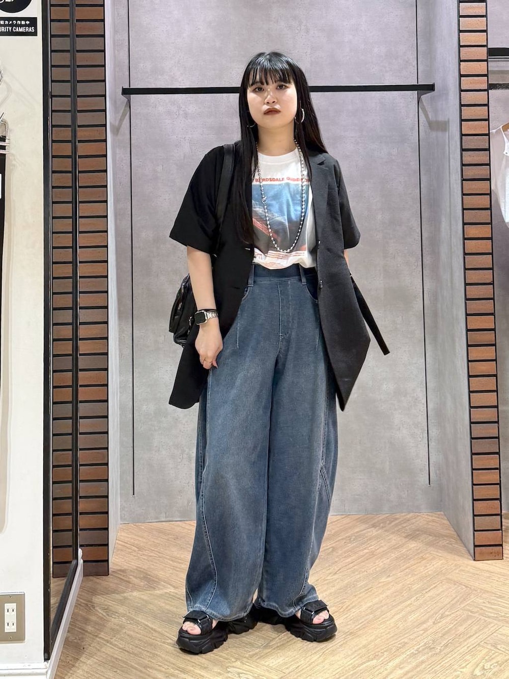 ブラック系のショルダーバッグ、ブルー系のデニムパンツ、ブラック系のサンダルを着用したレディースの春コーディネートの2枚目の写真