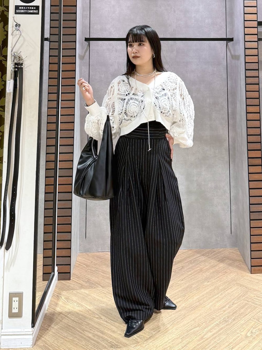 ブラック系のキャミソール、ホワイト系のカーディガン/ボレロ、ブラック系のトートバッグを着用したレディースの春コーディネートの7枚目の写真